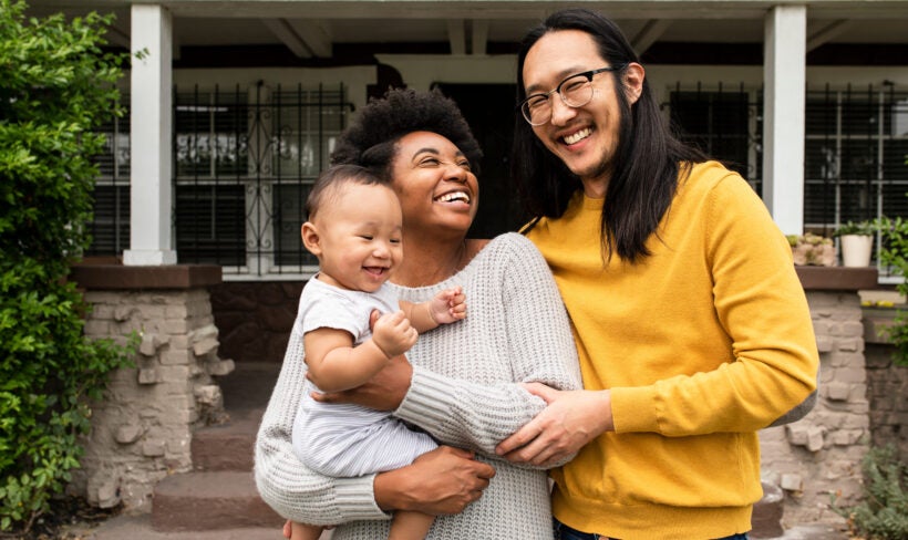 Smiling multiethnic family standing in front of the house