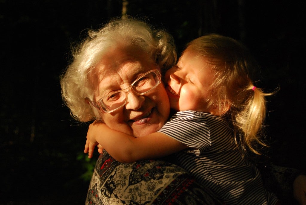 An older lady being shown affection with a hug from a smiling girl