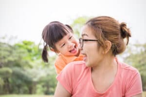 Asian mother and daughter playing playfully in the park.