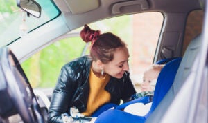 Smiling mother securing her baby into and infant car seat