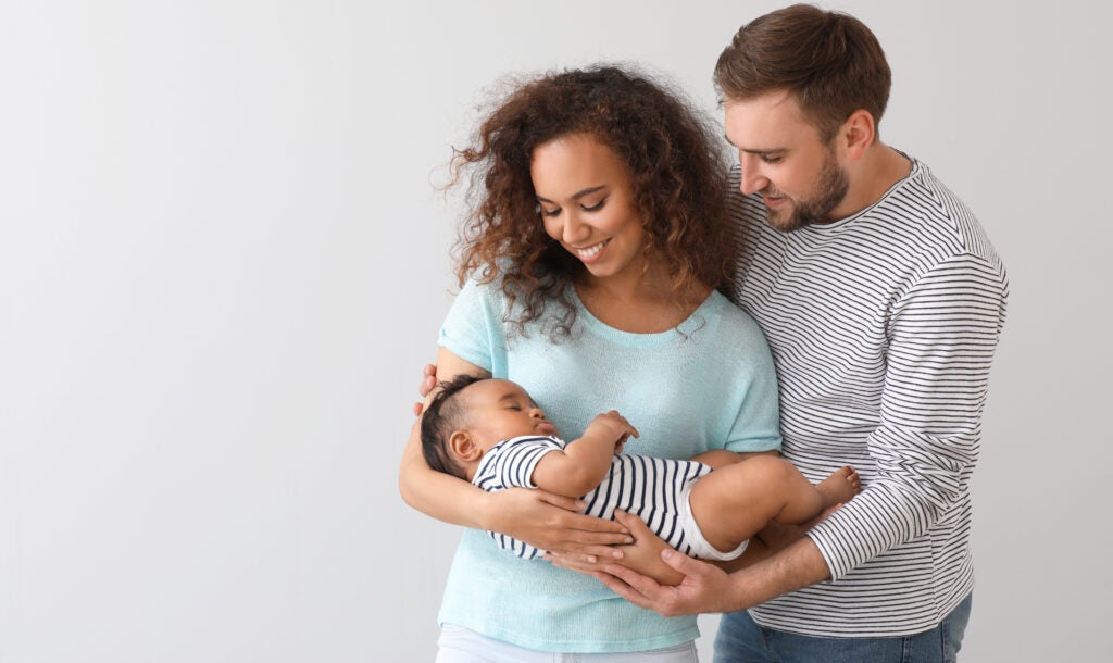A family portrait showing a happy, interracial family on light background