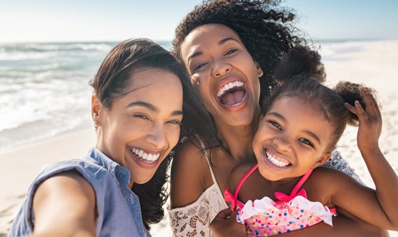 3 generations of women smiling and taking a selfie on a beach