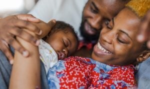 New parents, smiling and cuddling with their newborn infant