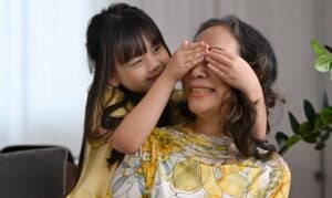 A little girl playing peek-a-boo over her grandmother's eyes