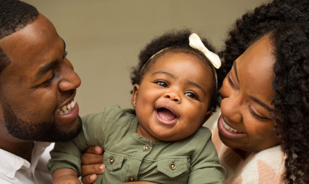 Smiling, happy parents with their infant being held between them