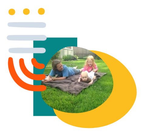 Bryn Fortune plays with her two young grandchildren on a blanket, surrounded by grass.